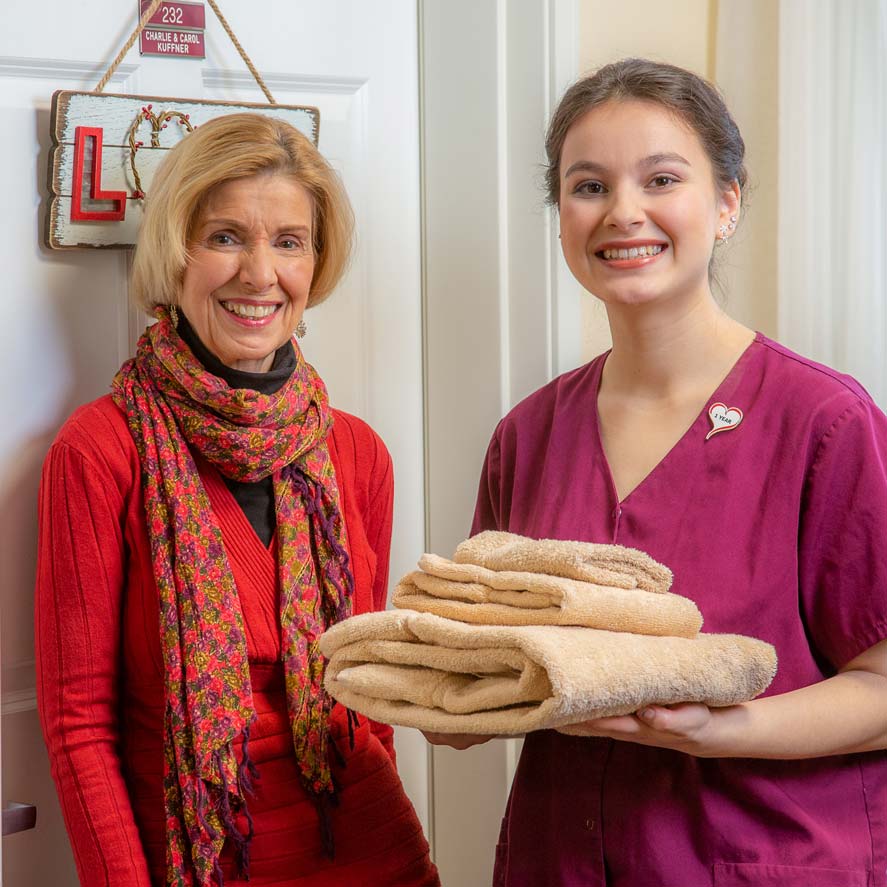 A team member delivering fresh linens to a resident at Providence Meadows